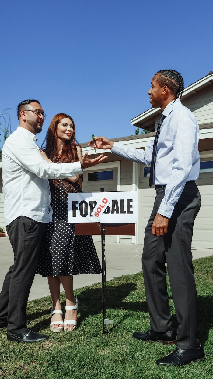 Couple receiving keys from realtor in front of newly sold house. Perfect real estate imagery.